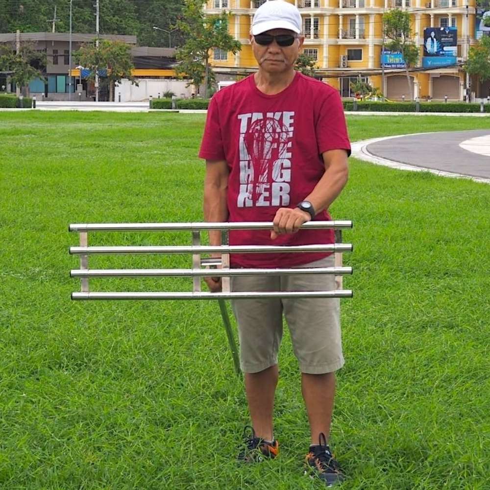 A man on a lawn holding the stainless steel levelling rake grate